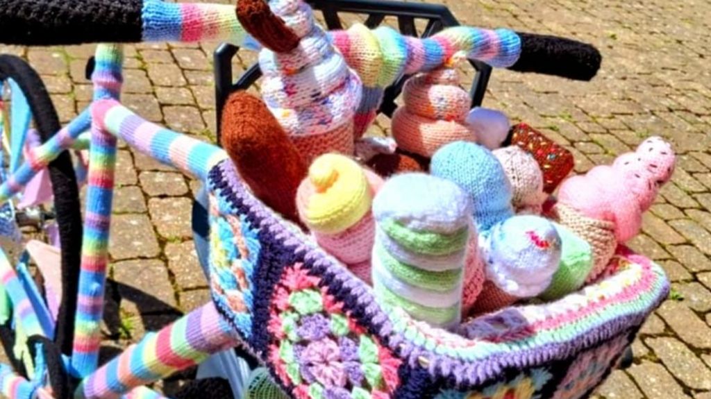 Knitted ice cream bike with basket made of pink, blue, green, black and orange yarn