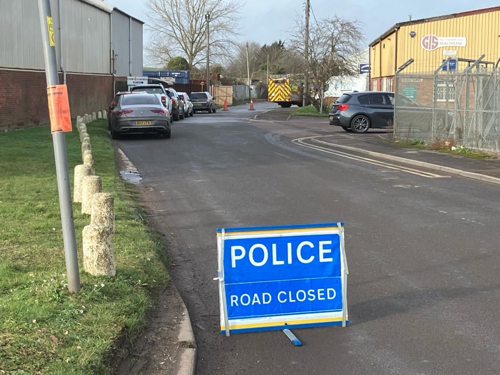 Police road closed sign with a fire engine in the background
