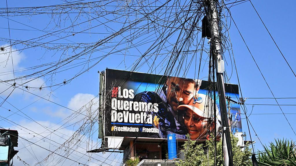 A spider web of power lines can be seen in front of a billboard calling for the releas of ousted Venezuelan President Nicolas Maduro and his wife, Cilia Flores, inthe Petare neighborhood, Caracas.