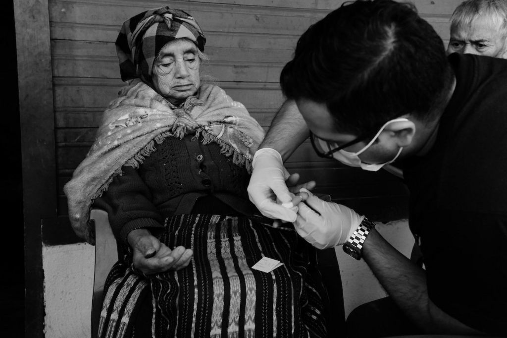 Forensic anthropologist Fernando Granados takes the DNA sample of Juliana Tum Sicá, 78, at her home. Xexuxcap, Nebaj, Quiche, Guatemala. February 10, 2021.