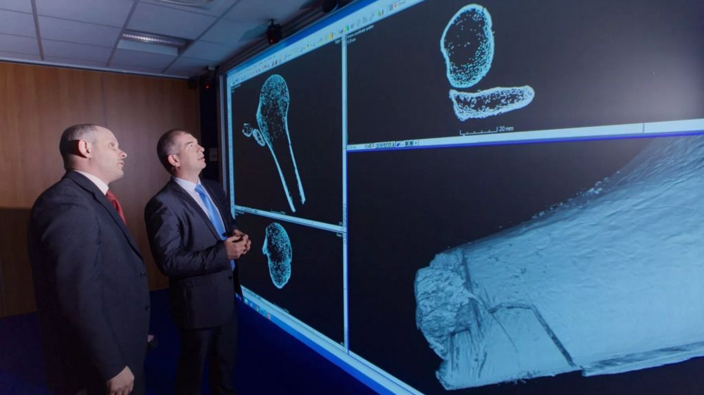 Two men stare at in-depth images of a bone on a screen