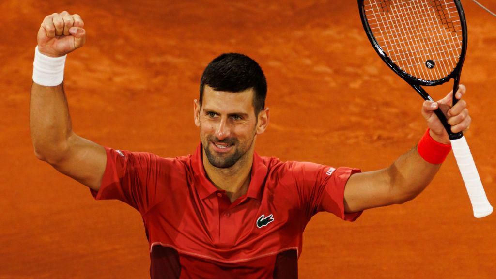 Novak Djokovic holds up his racquet in celebration