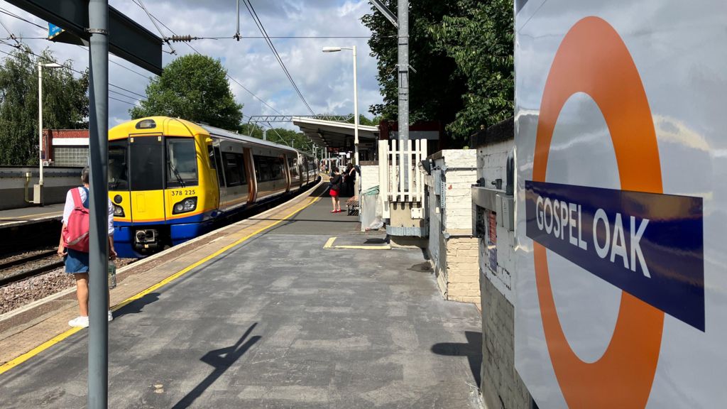 Orange Overground roundel at Gospel Oak Overground station as a yellow-fronted train arrives on the platform