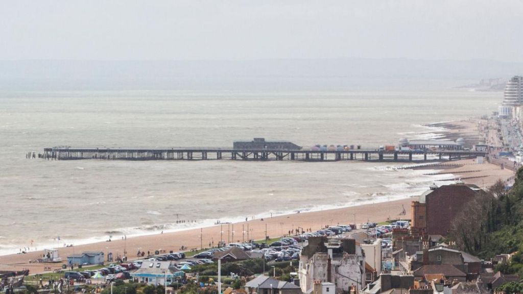 A seaside pier is visible from a distance.