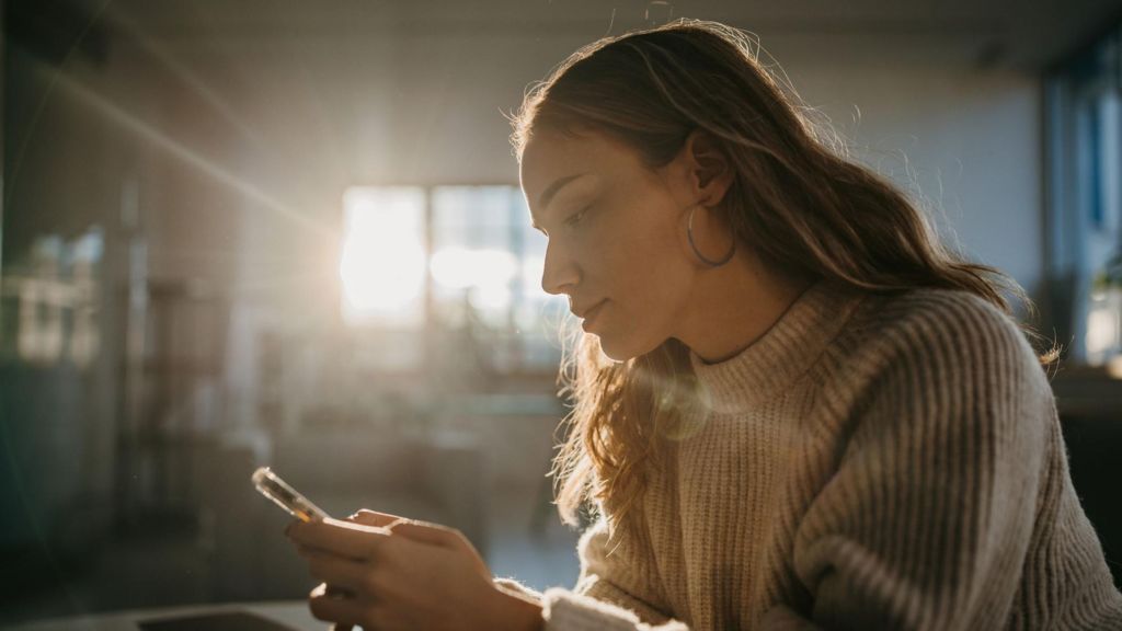 Young woman using smartphone at home.