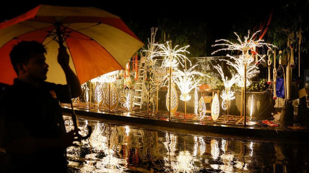 A man with an umbrella walks past decorations outside Antilia, the home of businessman Mukesh Ambani ahead of his son Anant Ambani's wedding to Radhika Merchant in Mumbai,