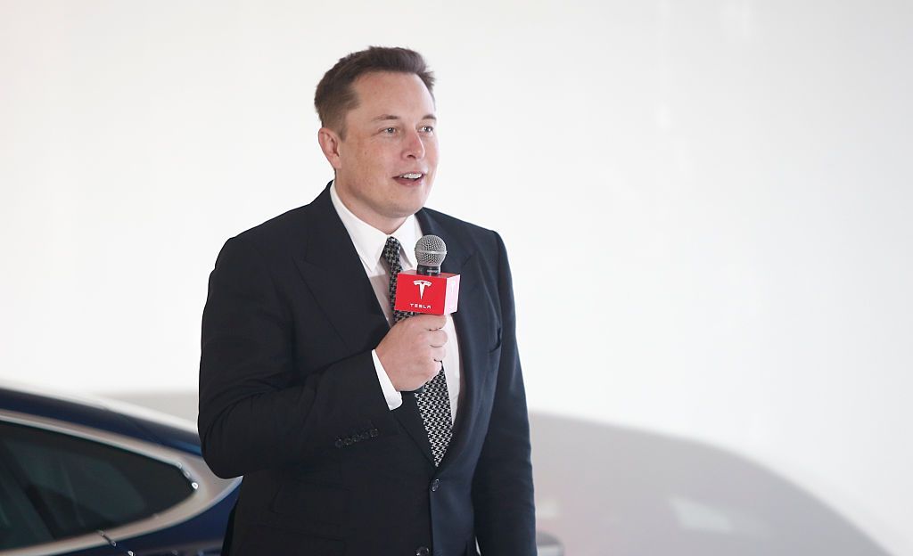 Elon Musk standing in front of a Tesla