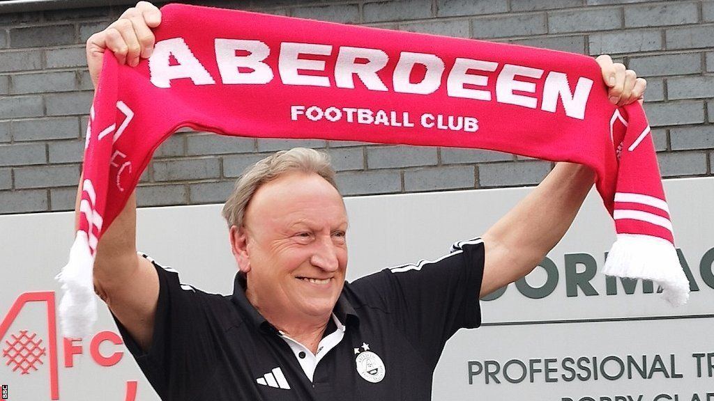 Neil Warnock holds an Aberdeen scarf above his head