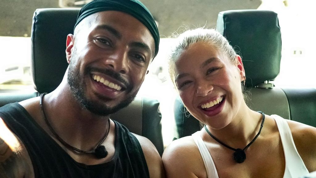 Tyler West and Molly Rainford smiling together in the back of a vehicle during the race