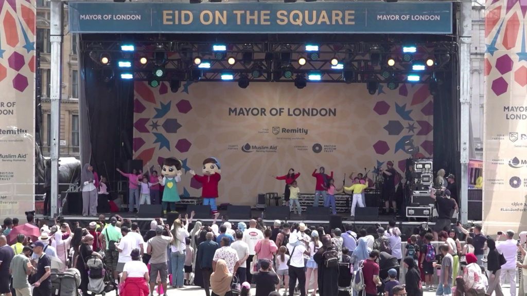 Children dancing to music on a big stage in front of crowds of families