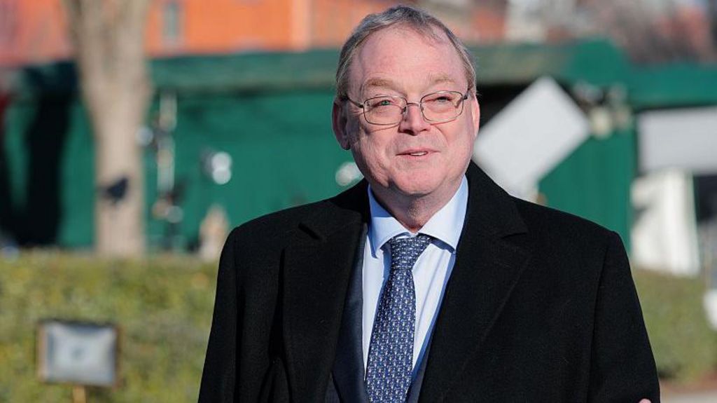 Director of the National Economic Council Kevin Hassett, wearing a black coat, a blue shirt and blue and white patterned tie speaks to reporters.