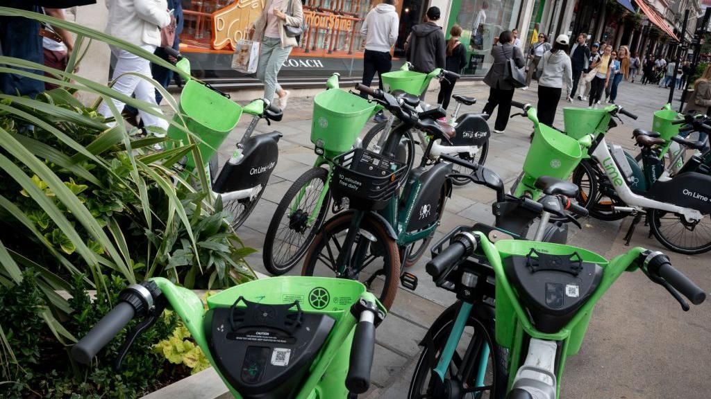 Members of the public walk past many Lime rental bikes that are stood on the pavement in Regent Street in September 2023