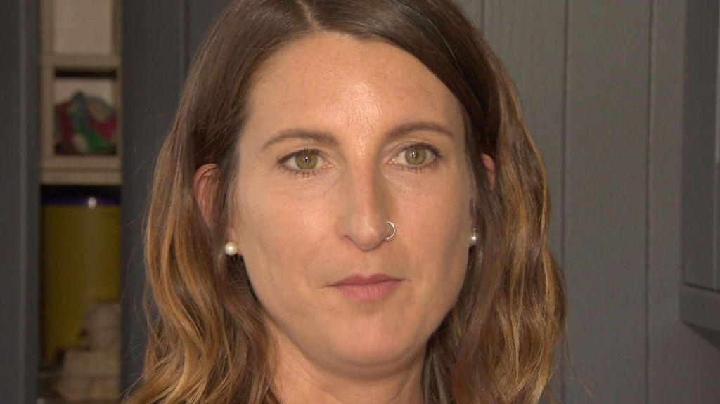 Jenny David at home with a picture and door behind her.