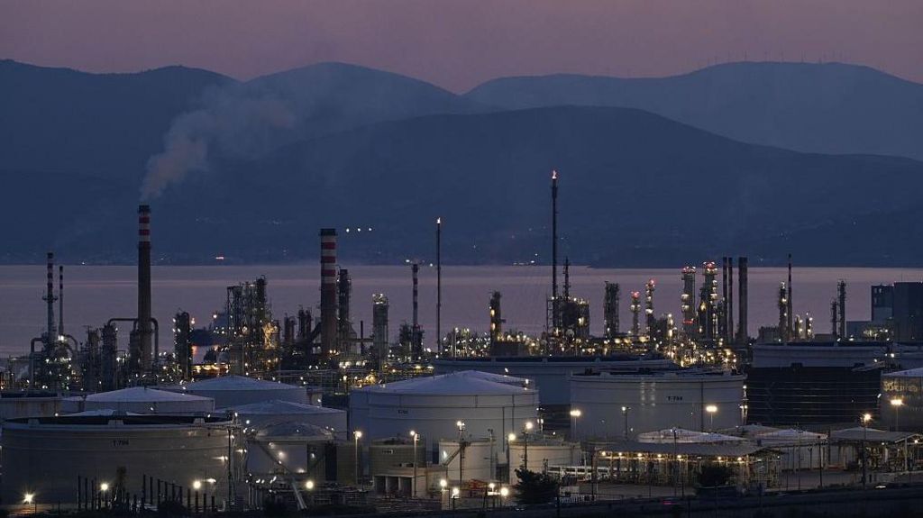 A view of the Motor Oil refinery in Agioi Theodoroi near Corinth, Greece during the evening. Behind the refinery, the sea and hills are visible but dark.