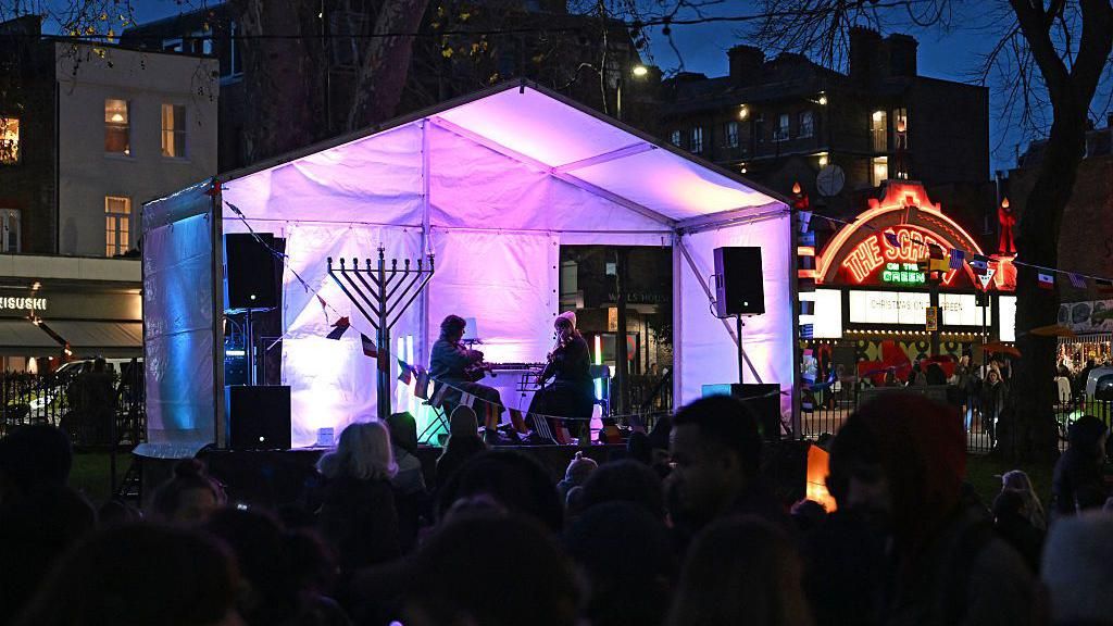 Musicians seen on a stage behind a crowd of people 