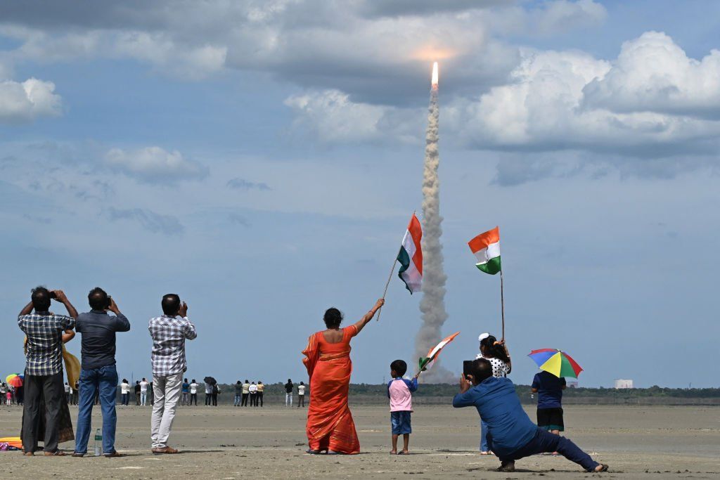 People wave flags as an Indian Space Research Organisation rocket blasts off