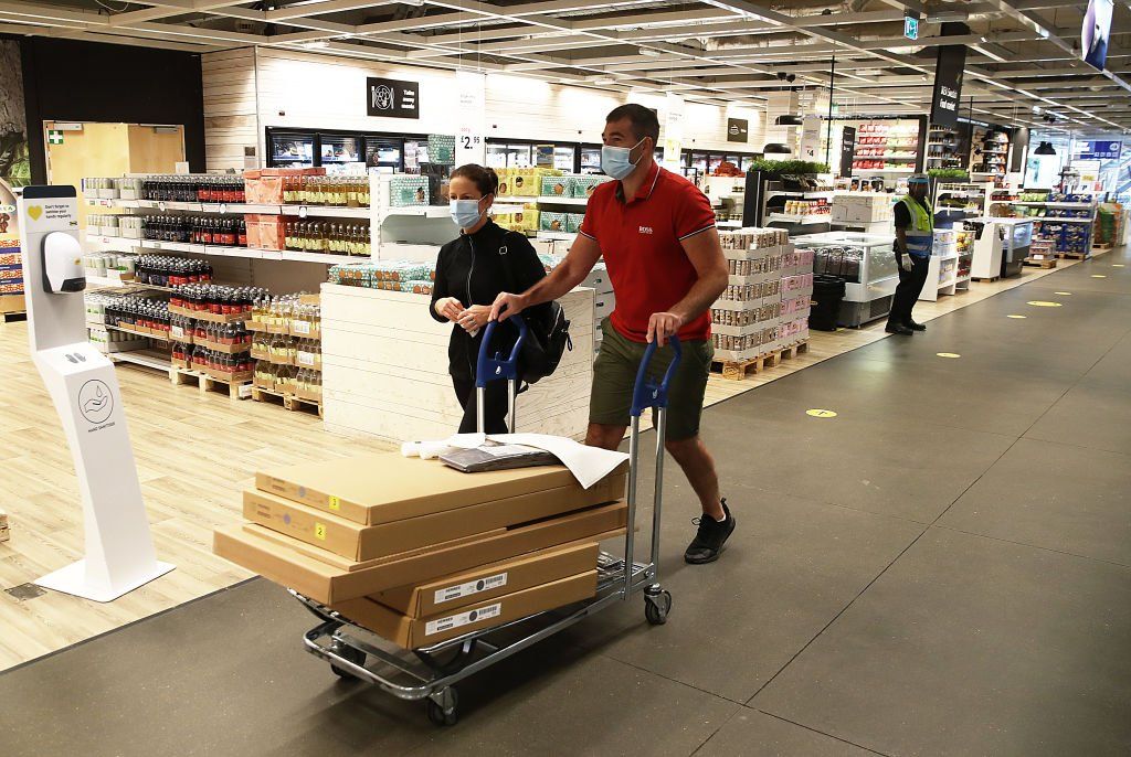 Man wheels trolley of flatpack items through Ikea