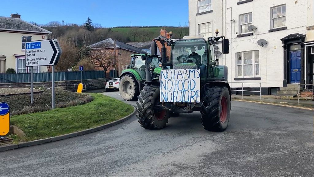 A tractor with a placard saying no farms no food no future drives through town
