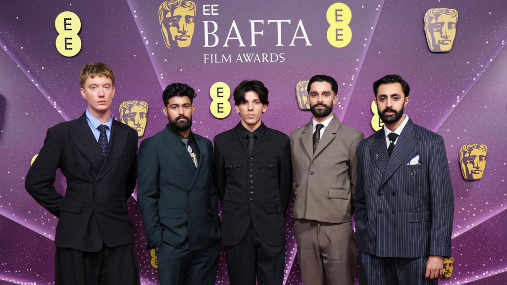 Aidan Robert Brooks, Sufiyaan Salam, Luís Hindman, Eben Figueiredo and Gurjeet Singh in suits in a row in front of a Bafta Film Awards-branded backdrop
