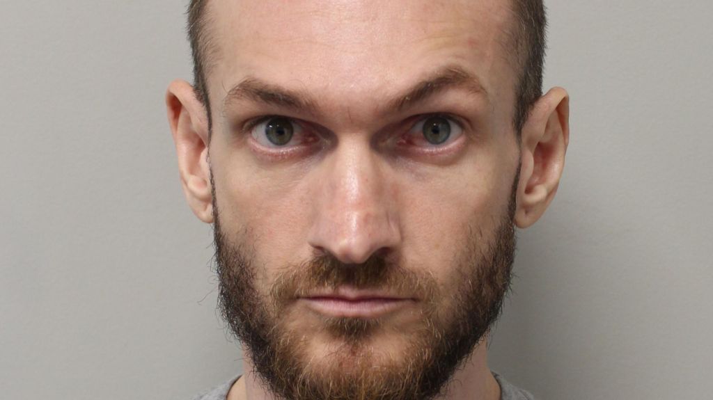 A mugshot of Marcus Arduini Monzo who has been found guilty at the Old Bailey of murdering 14-year-old Daniel Anjorin. He is wearing a grey jumper and is starring directly at the camera with a fuzzy beard