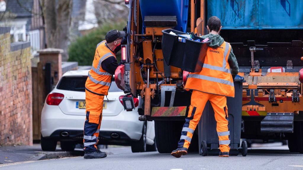 A council refuse collection employee collects rubbish