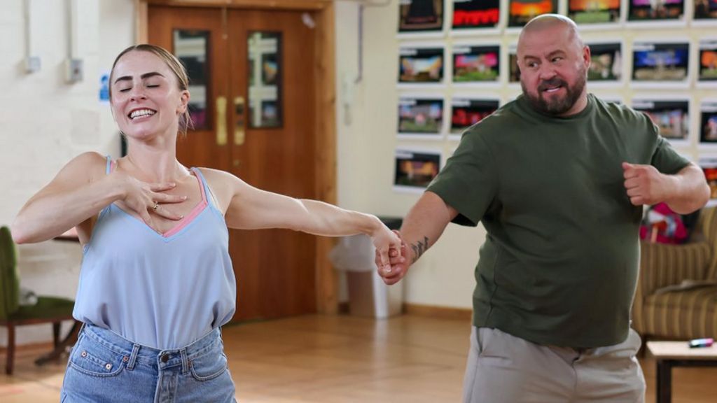 Emma Grace Arends and John May dance in rehearsals, holding hands with their arms outstretched