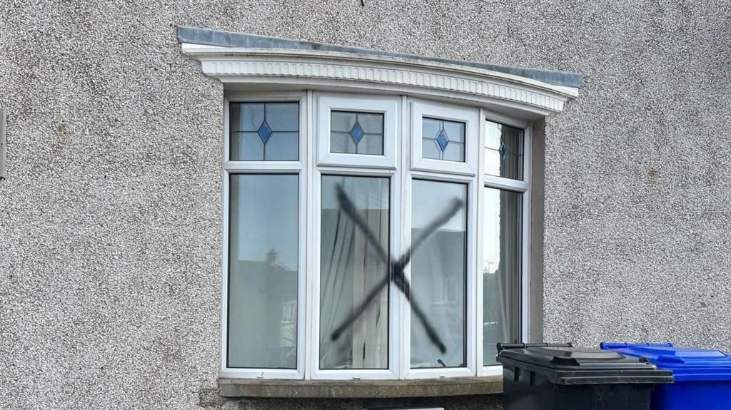 A black X was sprayed across the front window of the house