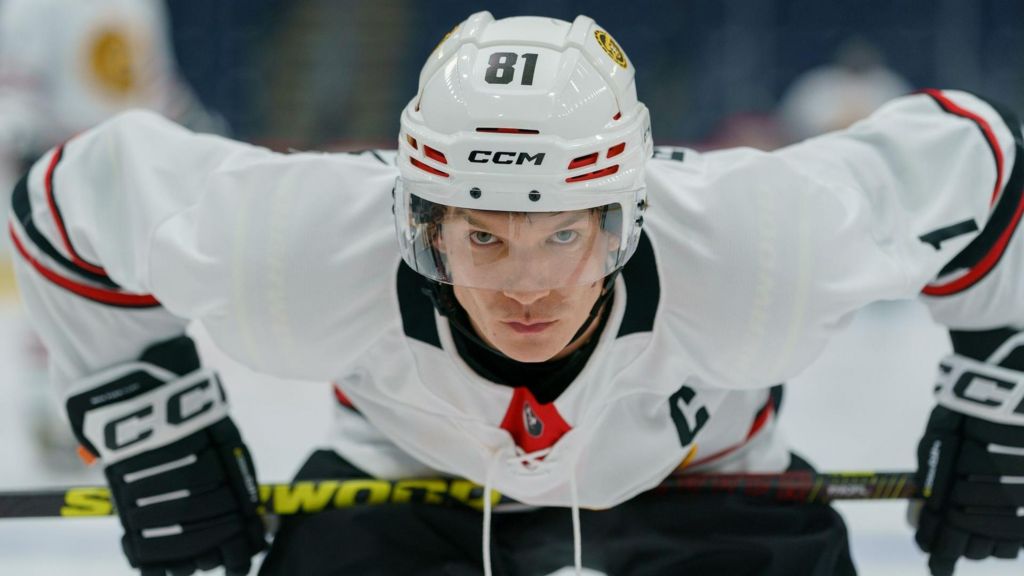 Connor Storrie in a scene from Heated Rivalry, in ice hockey outfit, bent over and looking intently ahead as if ready for action