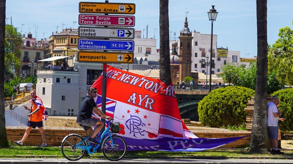 A man cycles past a Rangers supporters' flag in Seville