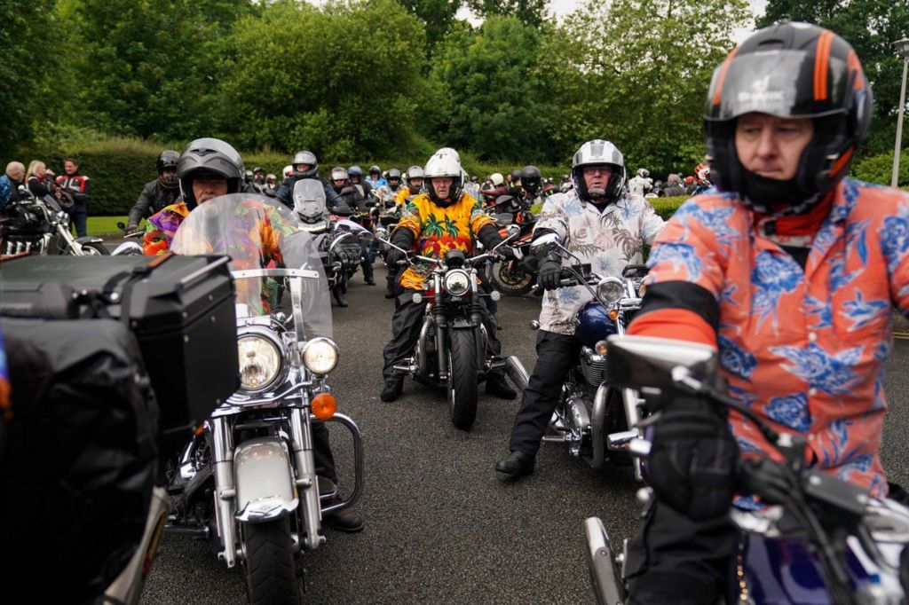 Motorcyclist dressed in Hawaian shirt taking part in a cavalcade in honour of the late-Dave Myers