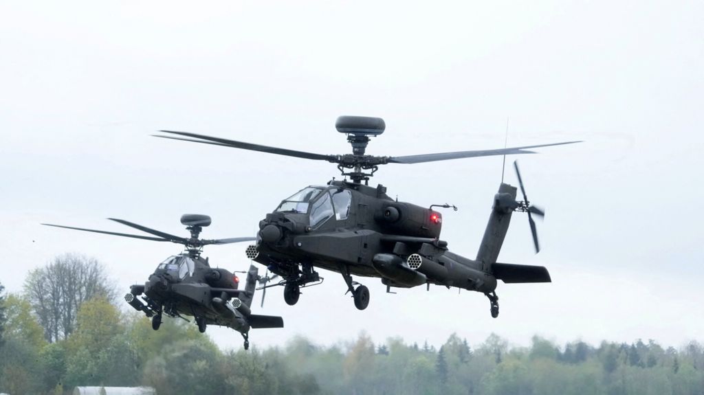 Two helicopters flying above the trees