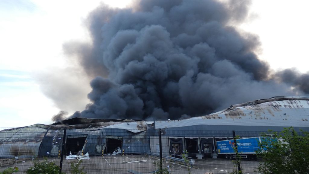 Smoke rises from the damaged warehouse