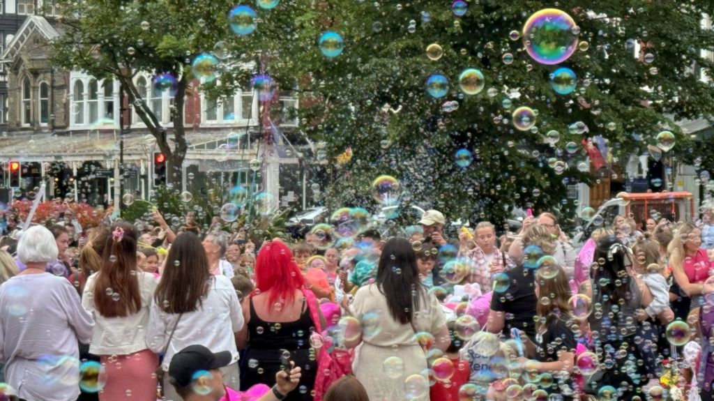 Children blew bubbles as others placed flowers and heart-shaped balloons in front of The Atkinson arts centre in remembrance of the victims of the stabbing attack