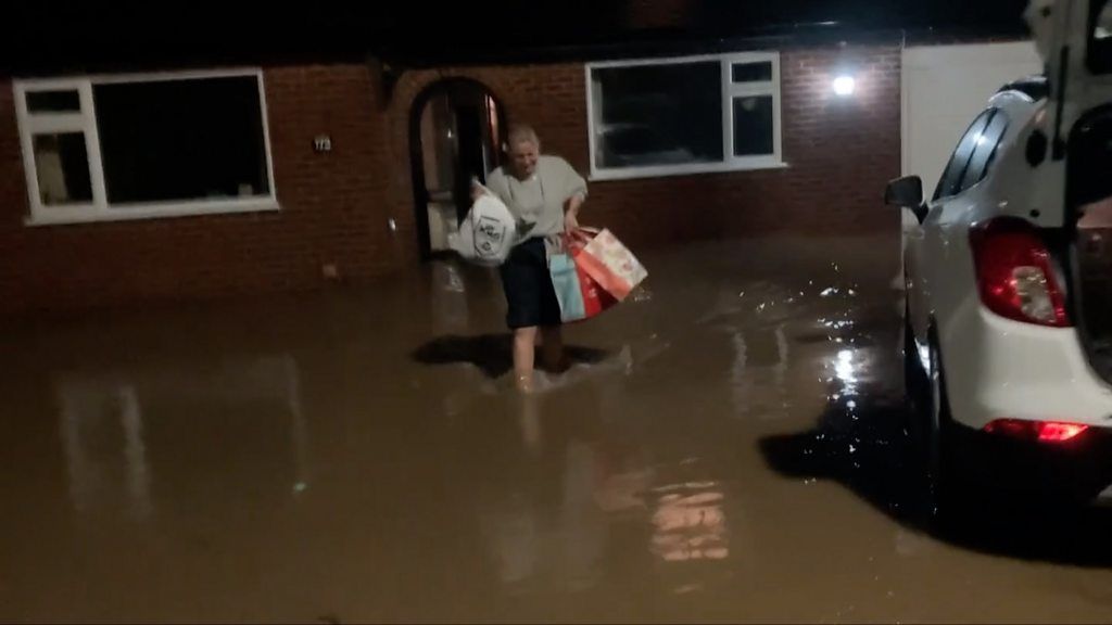 Woman carrying bags from her home in flooding