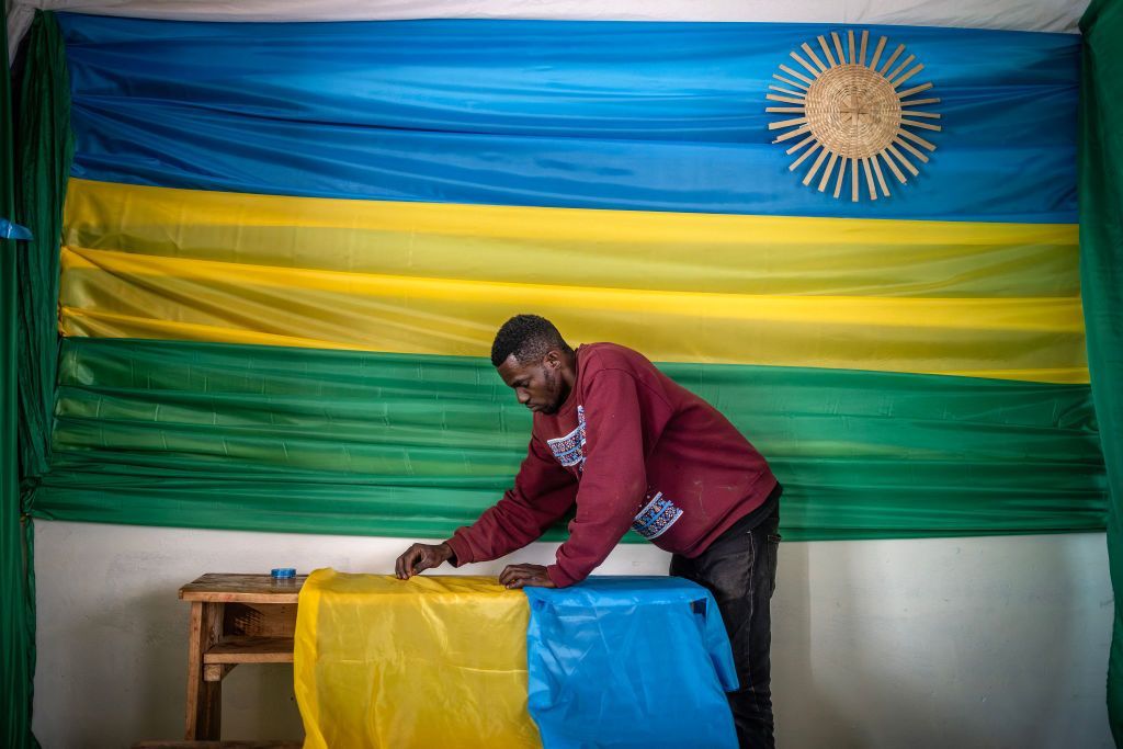 a man decorates this polling station in Kigali with green, yellow and blue.