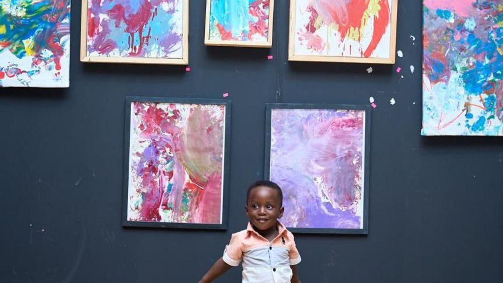 A toddler standing in front of abstract paintings