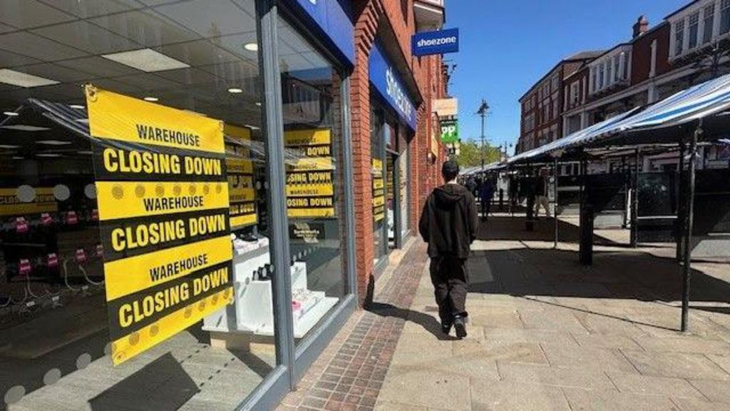Walsall shopping street, showing a yellow Warehouse Closing Down sale in the window of a shop and empty market stalls
