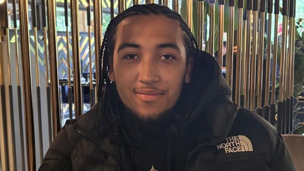 Keanu Harker smiles while wearing a black jacket