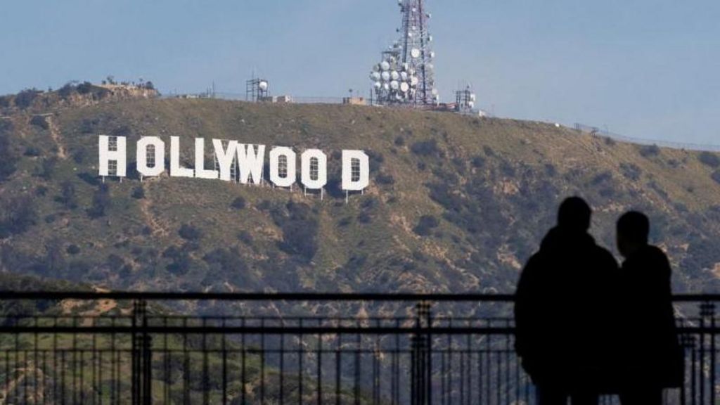 Two people silhouetted while standing and looking at the Hollywood sign