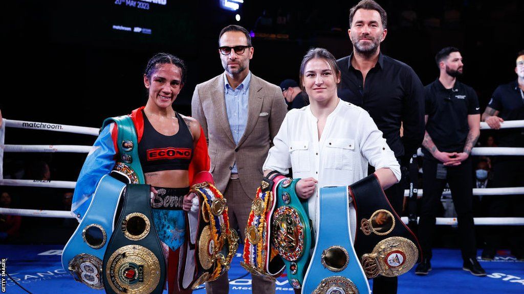 Amanda Serrano holds her titles beside Katie Taylor holding her belts in the ring after a fight
