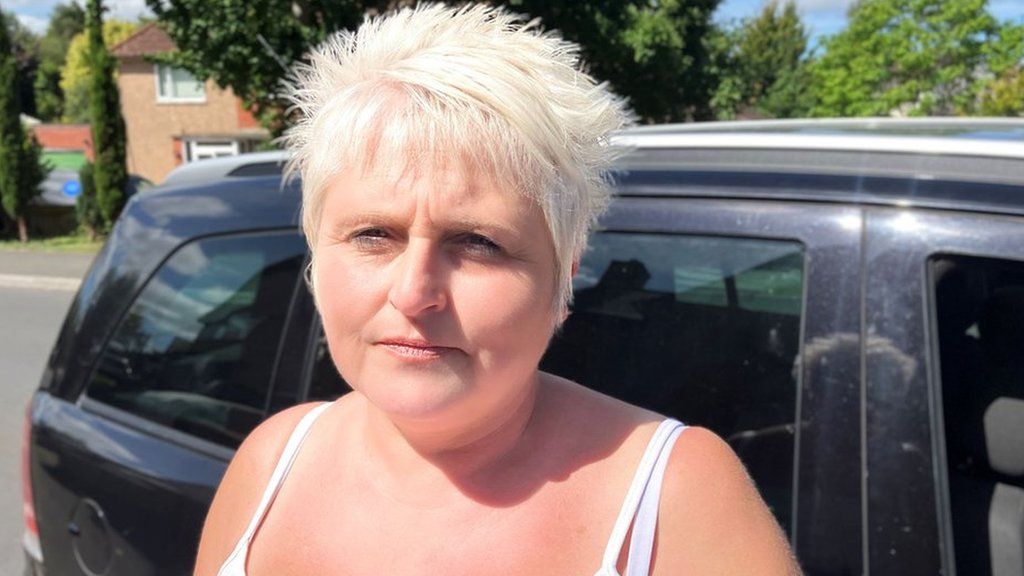 Head and shoulders shot of Dawn Sanders outside in a white vest top and with short blonde hair