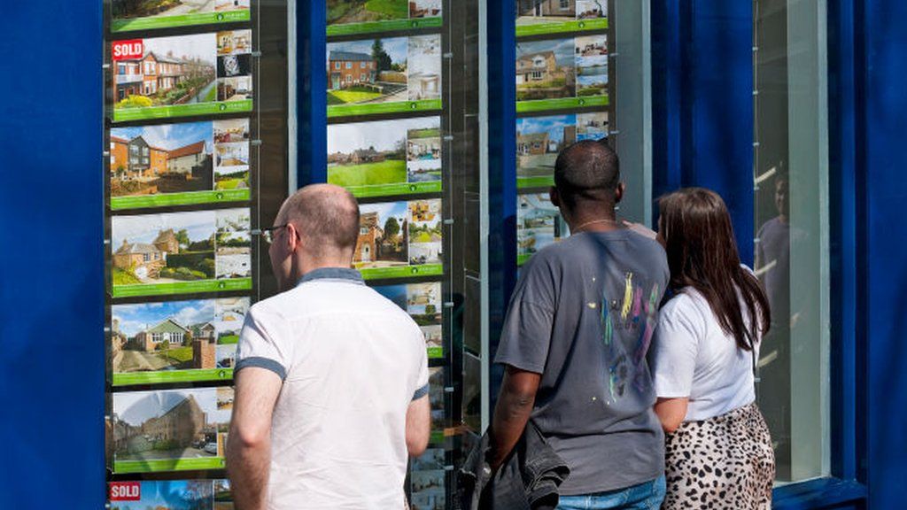 People looking in an estate agent's window.