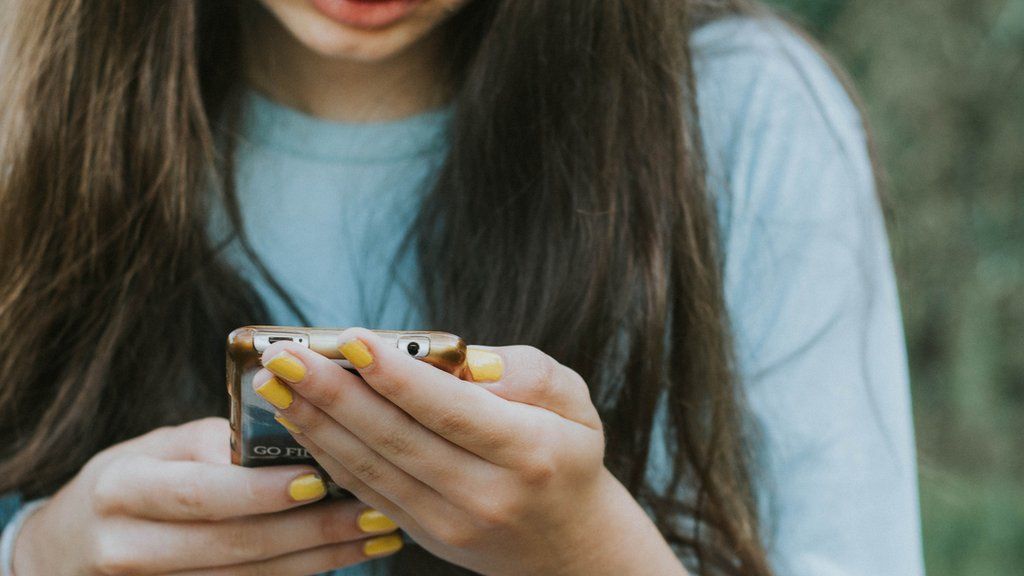 a teenage girl holding a phone in her hands