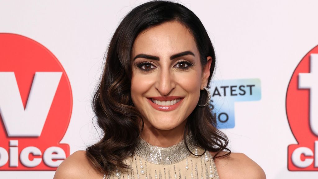 Punam Krishan smiling in a smart jewelled cream dress posing in front of a TV Choice-branded backdrop at the TV Choice Awards 2025