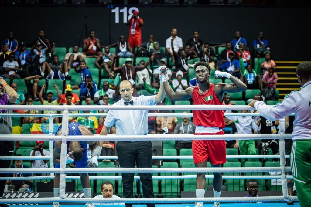 Adam Olaore in red kit with Nigerian flag on the chest has his hand held aloft by the referee as he wins the 2023 African Championship