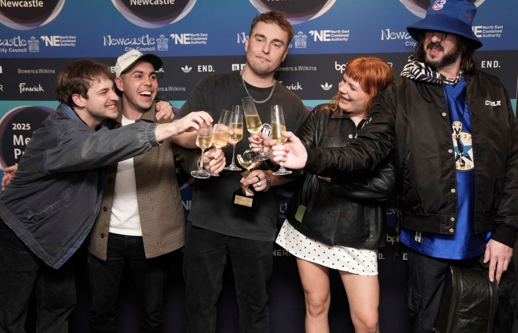 Sam Fender and his band clink together glasses of champagne as they celebrate winning the Mercury Prize