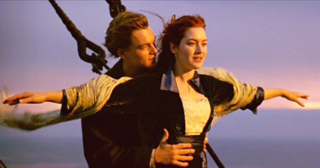 A scene from the movie Titanic where Jack holds Rose from behind while she has her arms out to the side on the bow of the ship.