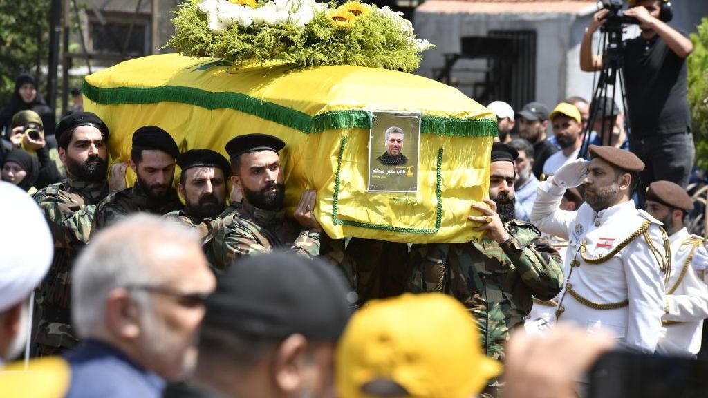 Taleb Abdallah's coffin is carried by men in military dress