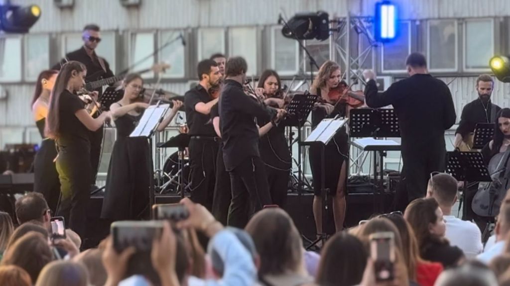 An orchestra playing on a rooftop to an audience