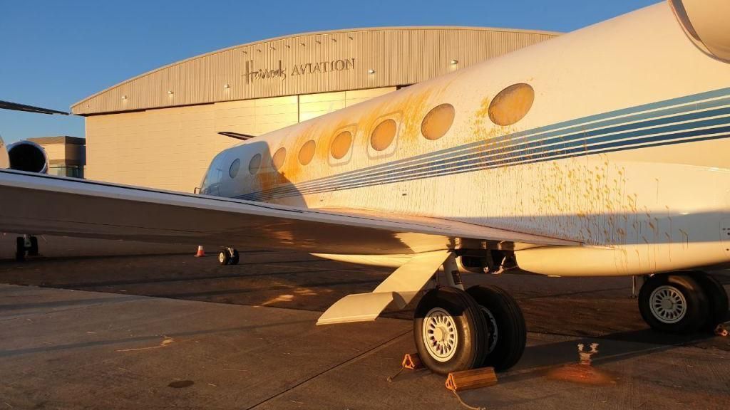 The side of a plane sprayed with orange paint on the tarmac